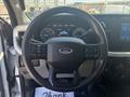 Steering wheel of a 2023 Ford F-350 SD with controls and the Ford logo prominently displayed