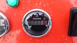 A digital hour meter showing 0000.0 hours on a circular display with a chrome border and water droplets on its surface