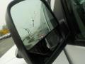 A close-up of the side mirror of a 2011 Chevrolet Express showing reflections and raindrops on the glass