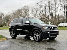A black 2019 Jeep Grand Cherokee parked with a sleek design featuring a distinctive front grille and large alloy wheels