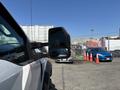 A 2017 Ford F-550 with large side mirrors parked in a lot with other vehicles and traffic cones visible in the background
