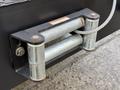 A close-up of a metal tow hitch connection with two cylindrical rollers and a metal frame mounted on a vehicle chassis