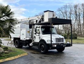 A 2015 Freightliner M2 bucket truck with a white body and front-mounted aerial work platform designed for lifting workers and equipment