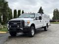 A 2015 Ford F-350 SD truck with a white exterior features a front grille guard work bed and high-clearance tires parked in a driveway