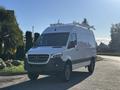 A 2024 Mercedes-Benz Sprinter 2500 van with a white exterior and black accents, featuring roof racks and rugged tires