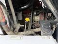 A close-up view of the engine compartment of a 2012 Global M4 featuring various hoses and a yellow oil dipstick with a label indicating engine oil level
