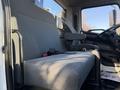 A gray fabric seat in the cab of a 2015 Hino 358 truck with a seatbelt and a visible armrest