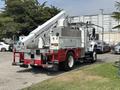 A 2012 International 7300 Workstar truck with a raised hydraulic lift arm and a storage compartment on the side