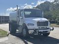 A 2022 Freightliner M2 106 truck with a white cab and silver accents featuring a large tank on the back and chrome front bumper standing on a paved surface