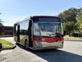 A 2016 Grande West Vicinity bus with a red and silver exterior is parked, featuring large windows and a modern design