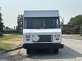 A white 2018 Ford Econoline with a flat front and large windshield is parked facing the camera, featuring a grill and a diamond-shaped utility box on the front