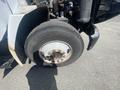 A close-up of the front tire of a 1997 Freightliner FL70 showing the wheel rim and tire tread details