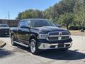 A black 2015 RAM 1500 pickup truck with chrome accents and a shiny grille parked at an angle showcasing its front and side profile