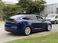 A blue 2020 Tesla Model X parked with rear angled view showing its sleek design and unique falcon wing doors