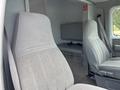 Interior view of a 1994 GMC Vandura 3500 showing two gray upholstered front seats and a metal storage compartment behind them