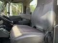 A driver's seat in a 2011 International 7500 truck with armrest and seat controls visible