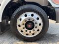 Close-up of a silver wheel rim with multiple bolts and a black Firestone tire mounted on a 2020 Peterbilt 330
