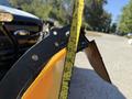 A close-up of a snow plow blade with a measuring tape beside it showing a measurement of 26 inches from the edge of the blade