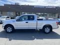 A silver 2015 Ford F-150 truck is parked with a double cab and black bed cover visible on the rear