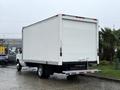 A white 2013 Ford Econoline box truck with a plain rear cargo area parked on a wet surface