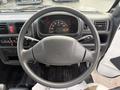 Interior view of a 2009 Suzuki Carry's steering wheel with dashboard visible and several controls on either side of the steering column