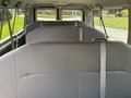 Interior view of a 2013 Ford E-350 Super Duty showing three rows of gray upholstered seating with seatbelts visible
