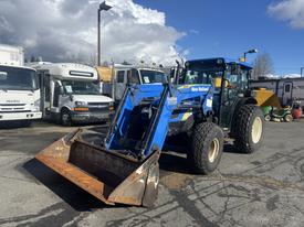 A 2010 New Holland T4050 tractor with a blue front loader and large tires parked on a lot