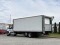 White 2019 Ford F-750 truck with a large cargo box and dual rear wheels parked at a loading area