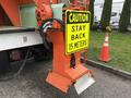 A 2012 International 7400 truck with an orange caution sign indicating to stay back 15 meters attached to its rear equipment