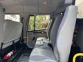 Interior view of a 1999 Freightliner FL80 showing the driver's seat and passenger seats with grey upholstery and a fire extinguisher on the floor