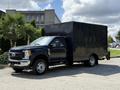 A black 2017 Ford F-550 truck with a large box cargo area is parked, featuring a chrome grille and multiple wheels