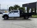 A white 2017 Ford F-450 Super Duty truck with a black flatbed parked on a concrete surface