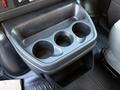 A black plastic cup holder with three circular compartments designed to hold cups or bottles in a vehicle interior