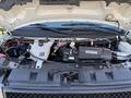 The engine compartment of a 2020 Chevrolet Express with visible engine components battery and various hoses and wires