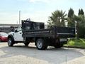 A 2022 Ford F-550 truck with a flatbed design parked with a black rear bed and aluminum sides
