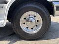 Close-up of a chrome wheel rim and black tire from a 1995 Ford F-250 with visible tread pattern and shiny surface reflecting light