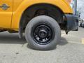 A close-up view of the black wheel of a yellow 2013 Ford F-250 SD showcasing the tire and rim design