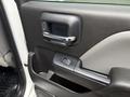 Close-up of the driver's side door panel of a 2016 GMC Sierra 1500 featuring a chrome door handle and power window control button
