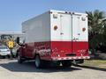 A red and white 2007 GMC C4500 TopKick box truck viewed from the rear with two orange lights on the upper corners and a double door at the back