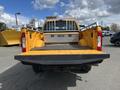 A yellow 2017 Ford F-250 SD truck with a flatbed and open tailgate is shown from the rear angle