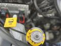 A close-up view of a yellow coolant reservoir cap and a yellow fuel indicator cap inside the engine compartment of a 2015 Jeep Grand Cherokee