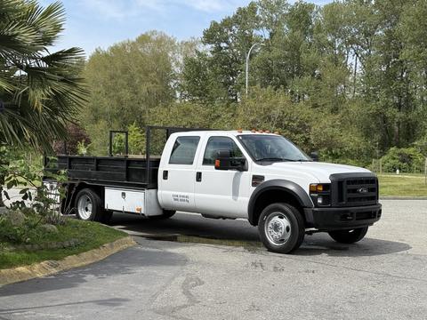 A 2008 Ford F-550 truck with a cab and flatbed design is parked with a white body and black flatbed visible in the foreground