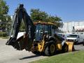A 2013 John Deere 710K backhoe loader with a yellow and green color scheme featuring a front loader and a large rear excavator bucket