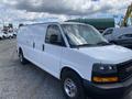 A 2023 GMC Savana van with a white exterior and chrome wheels parked in a lot