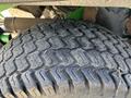A close-up of a tire from a 2021 John Deere 1575 showing a tread pattern with visible wear and dirt particles embedded in the grooves