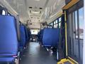 Interior view of a 2020 Chevrolet Express showing rows of blue seats and a driver's area at the front with controls and a windshield
