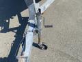A close-up of a 2013 Larson 238 boat trailer's adjustable tongue jack with a crank handle and a wheel at the base for maneuvering the trailer