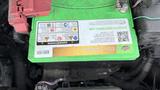 A green battery with warning labels and a QR code is prominently displayed in the engine compartment of a 2019 Nissan Kicks