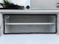 A storage compartment on a 2010 Ford F-550 with a black rubber seal and two horizontal shelves inside