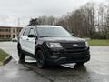 A 2019 Ford Explorer with a two-tone black and white exterior parked on a wet surface with a view of trees in the background